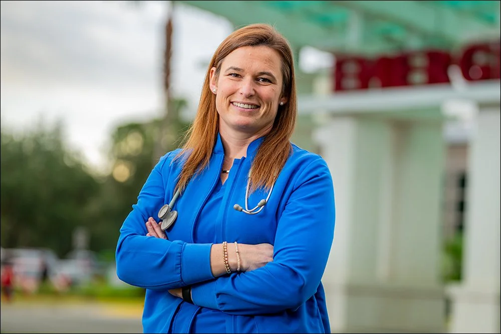 Female healthcare provider portrait outside hospital emergency entrance wearing stethoscope