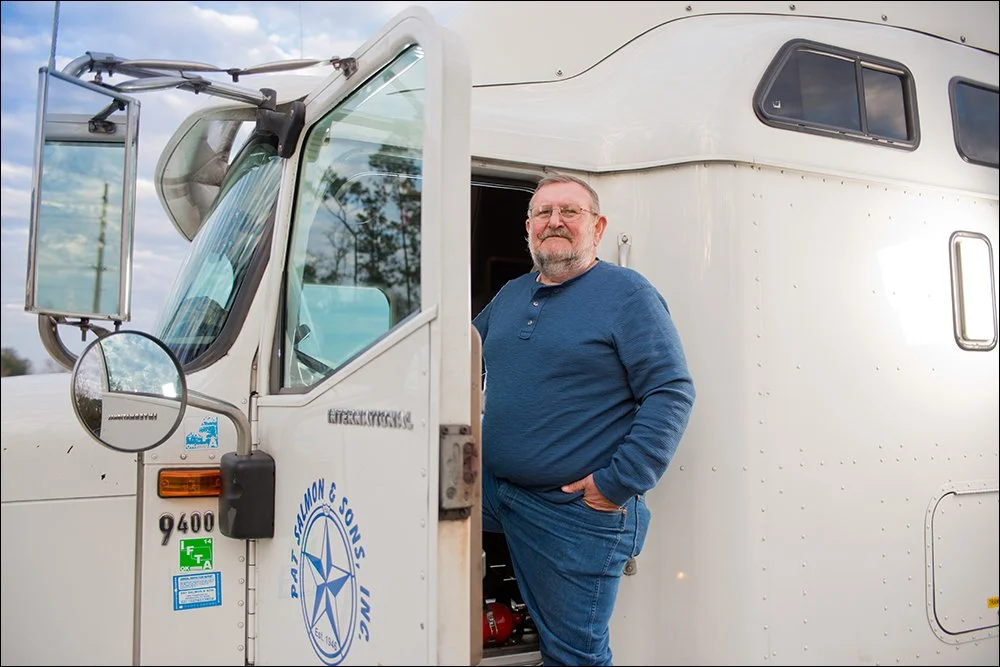 Truck driver standing at cab door of commercial vehicle on location