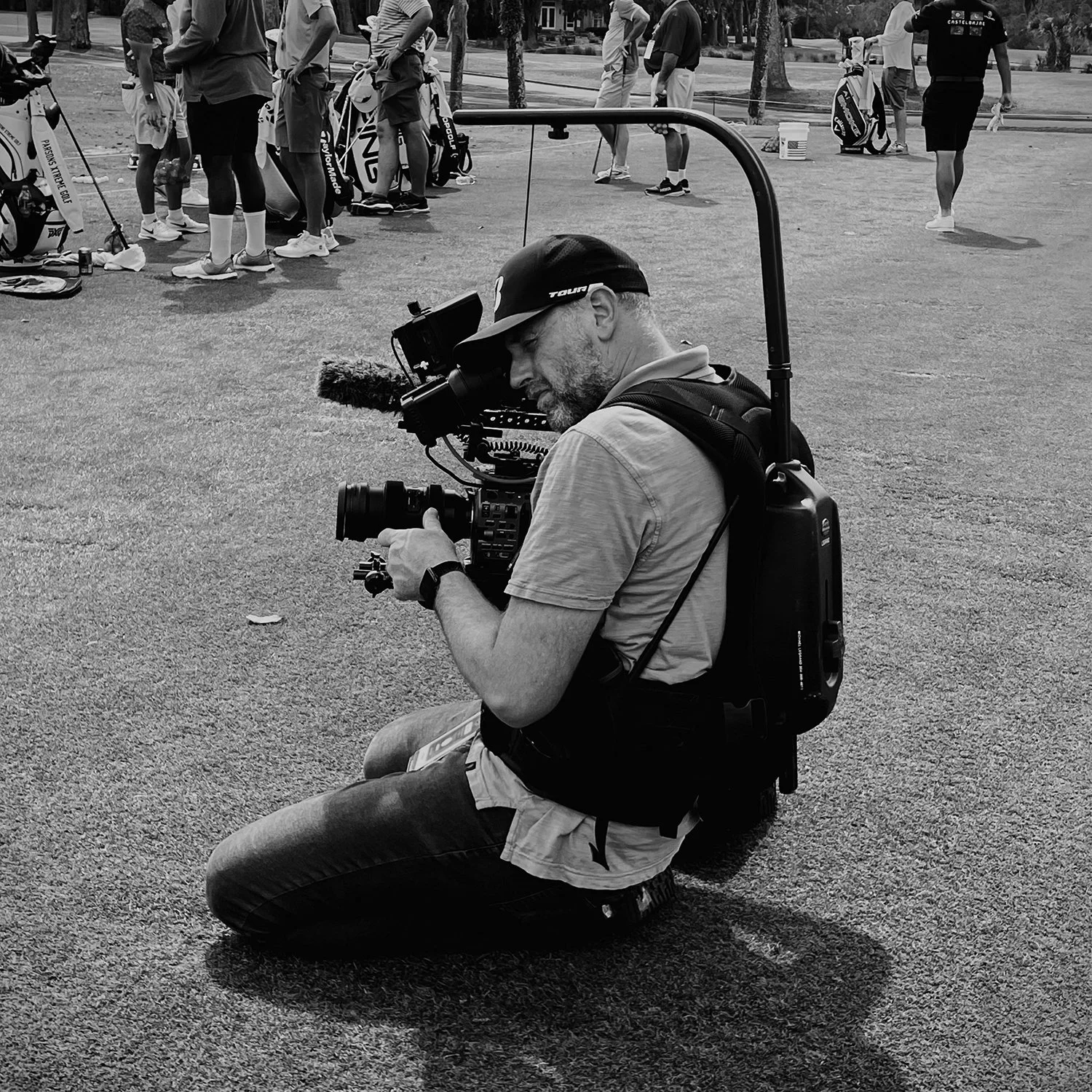 Cinematographer filming on a golf course during a professional sports video production shoot