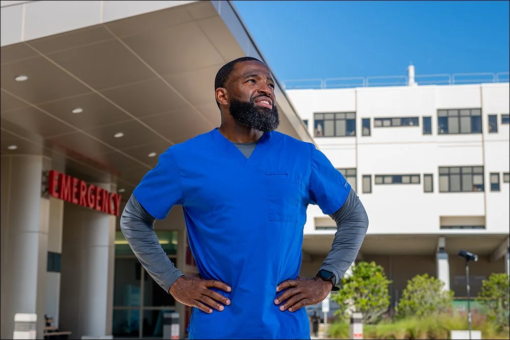 Healthcare provider portrait outside emergency department entrance wearing blue scrubs