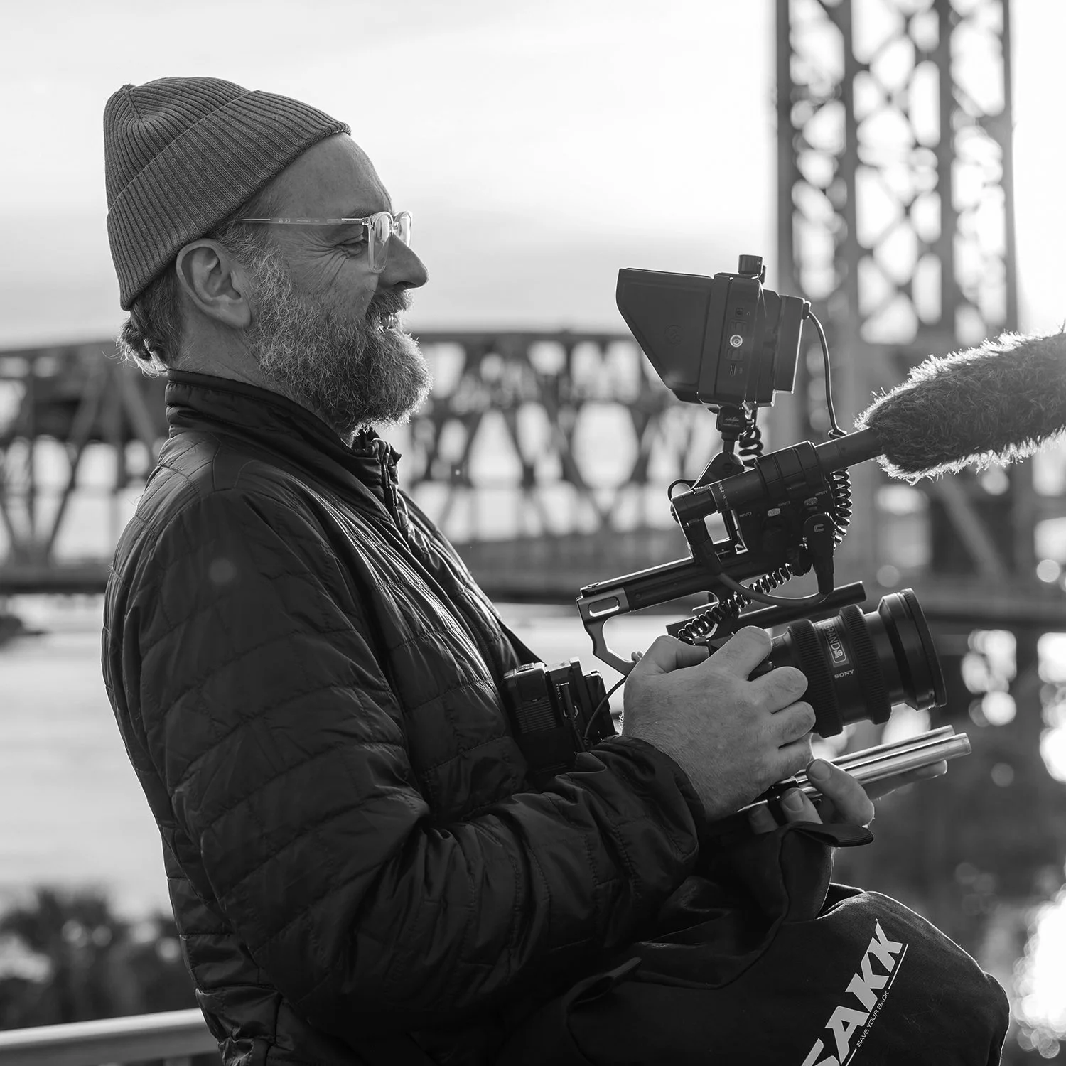 Cinematographer filming handheld video outdoors in Jacksonville, Florida during a commercial production shoot