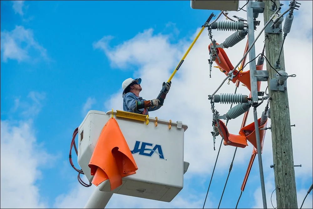 Utility worker performing maintenance on power lines from elevated bucket truck