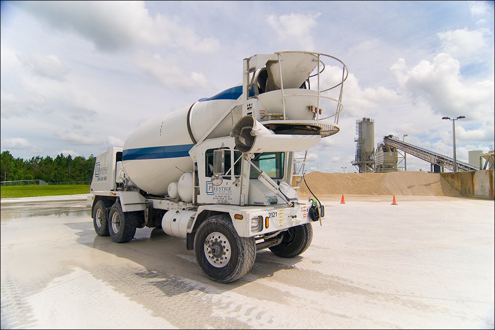 Concrete mixer truck parked at industrial construction site with materials and equipment