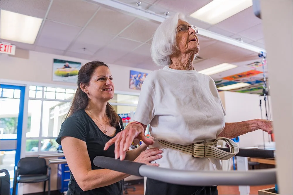 Elderly patient performing balance training with therapist support in rehabilitation clinic