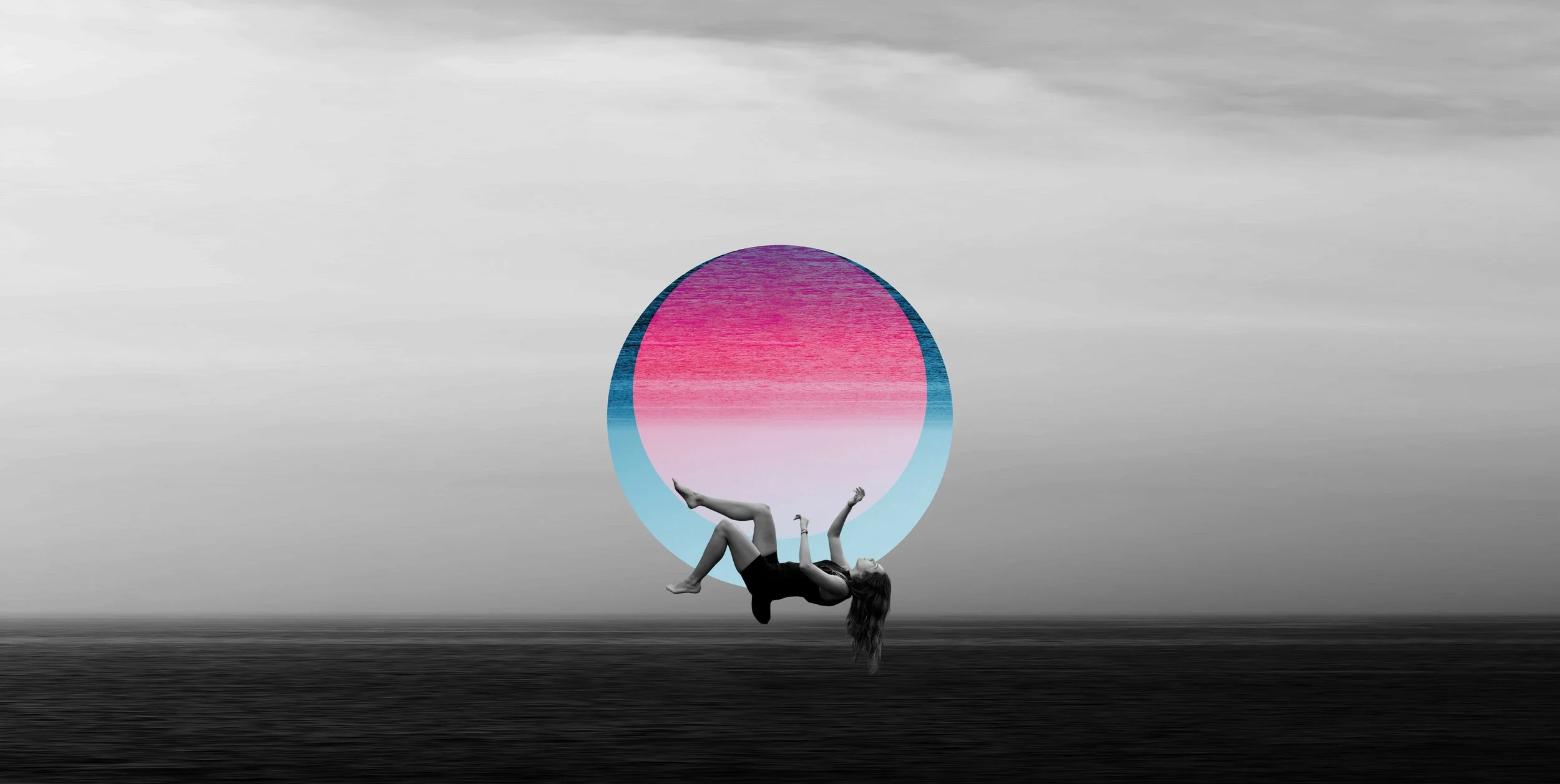 A woman lying on her back in an acro yoga pose with her legs extended upward and her arms supporting her upper body, positioned in front of a large, colorful oval shape with pink, blue, and purple gradient against a cloudy sky background.
