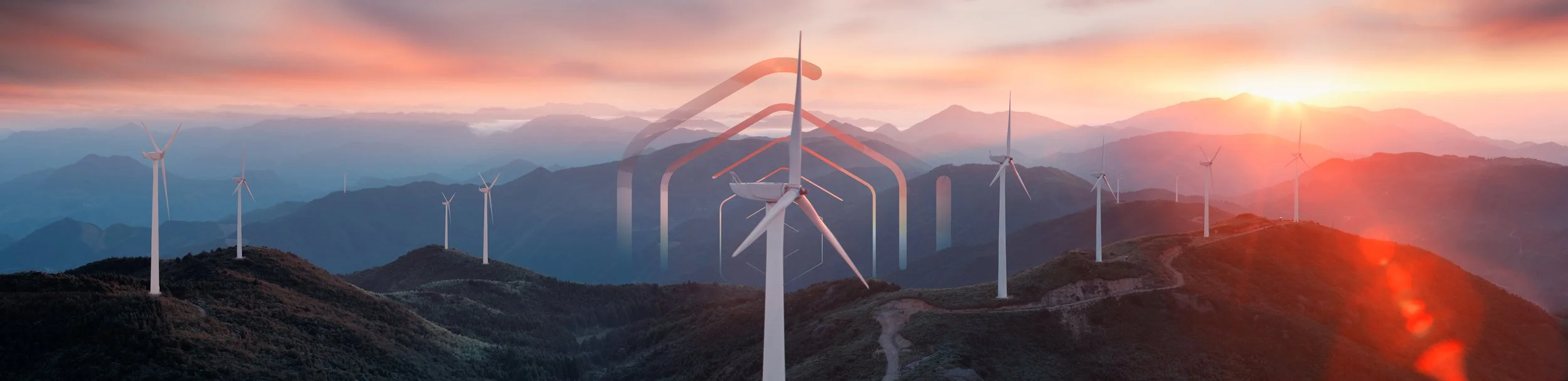 Wind turbines on a mountain ridge at sunset, with a lens flare effect and layered mountain ranges in the background.