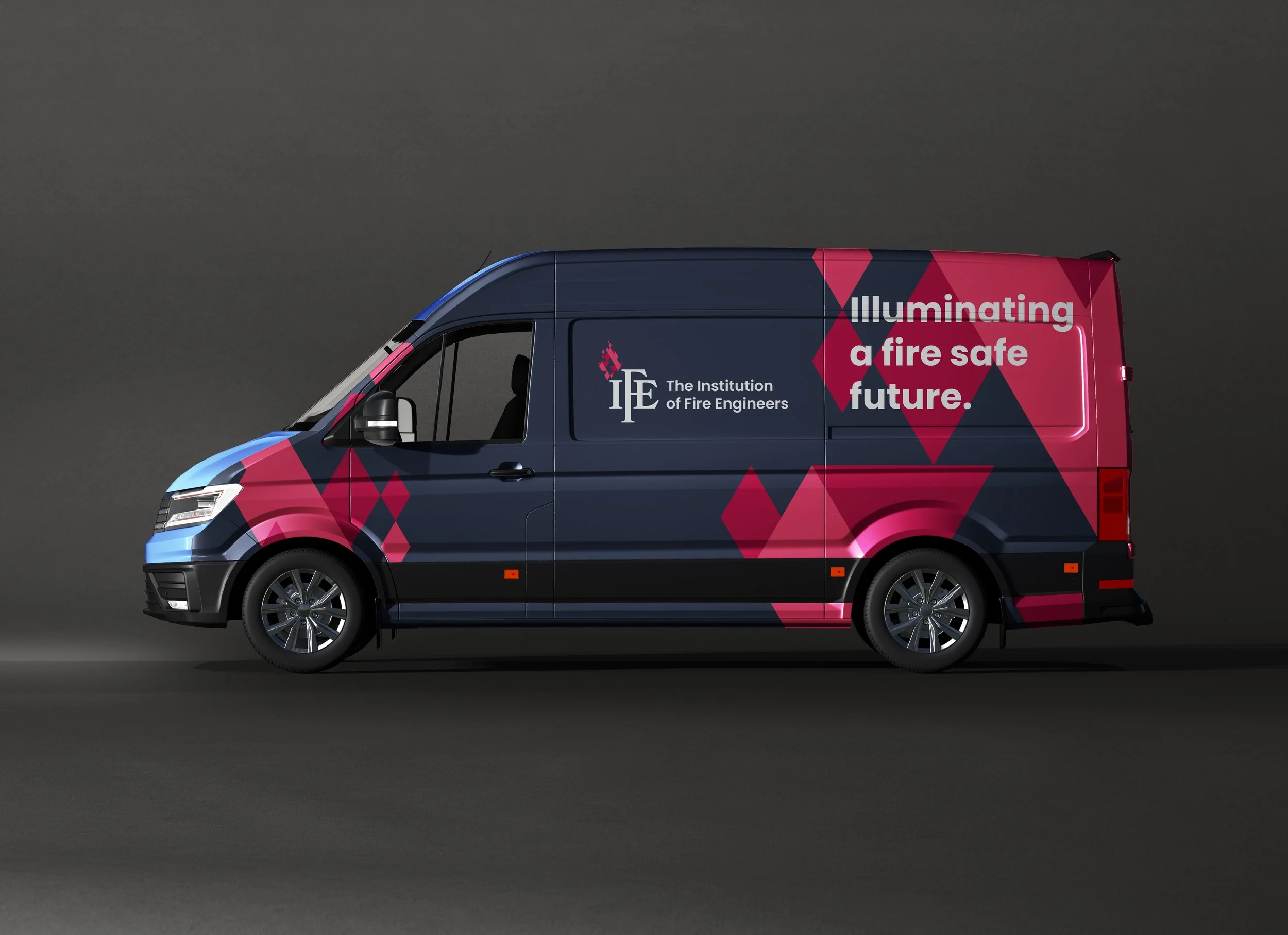 A dark blue delivery van with graphics and text promoting fire safety awareness. The text reads, 'Illuminating a fire safe future,' and includes the logo of The Institution of Fire Engineers.