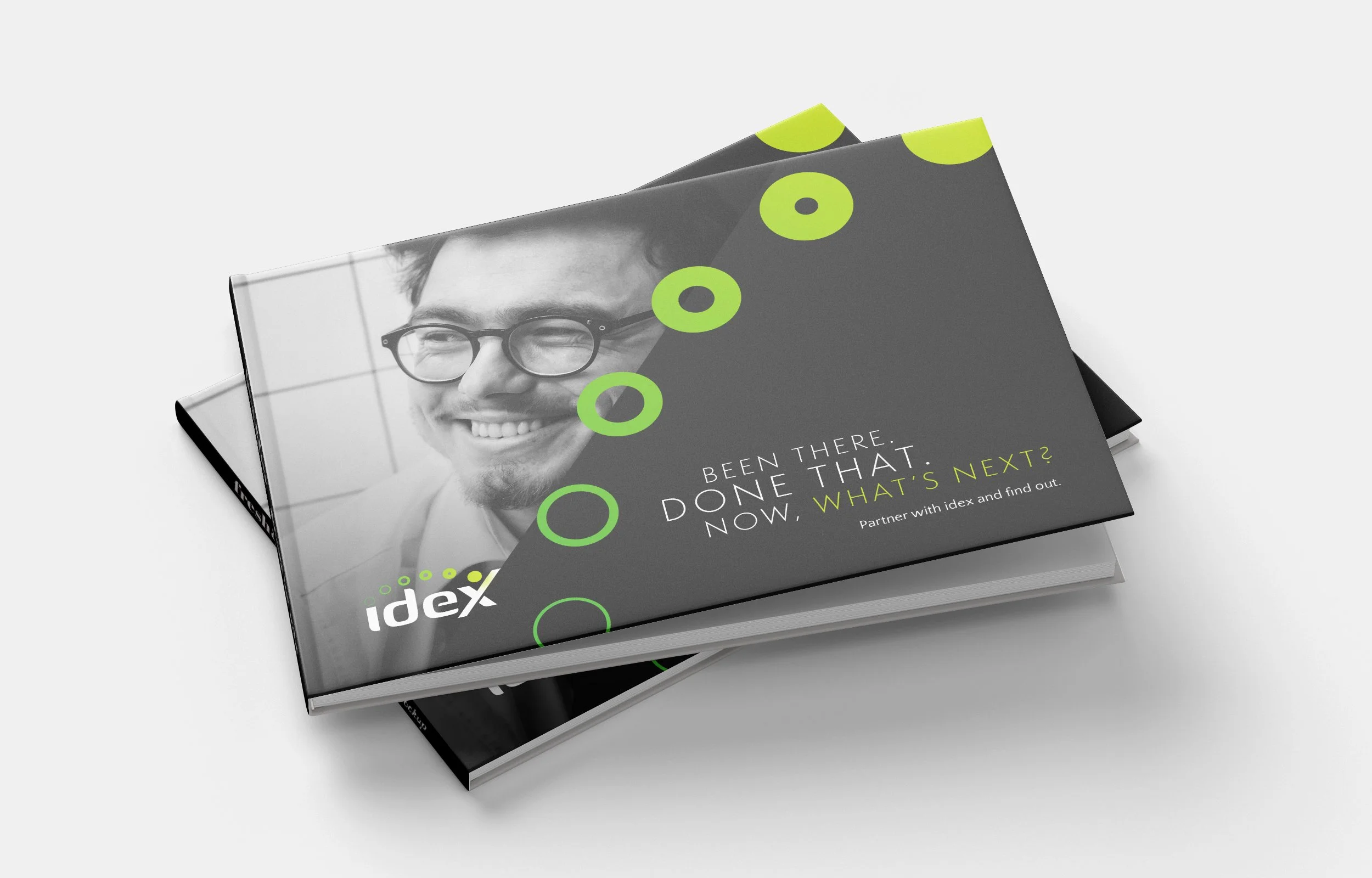Stack of black books with a gray cover, featuring a smiling man wearing glasses on the cover, and lime green circles and text.