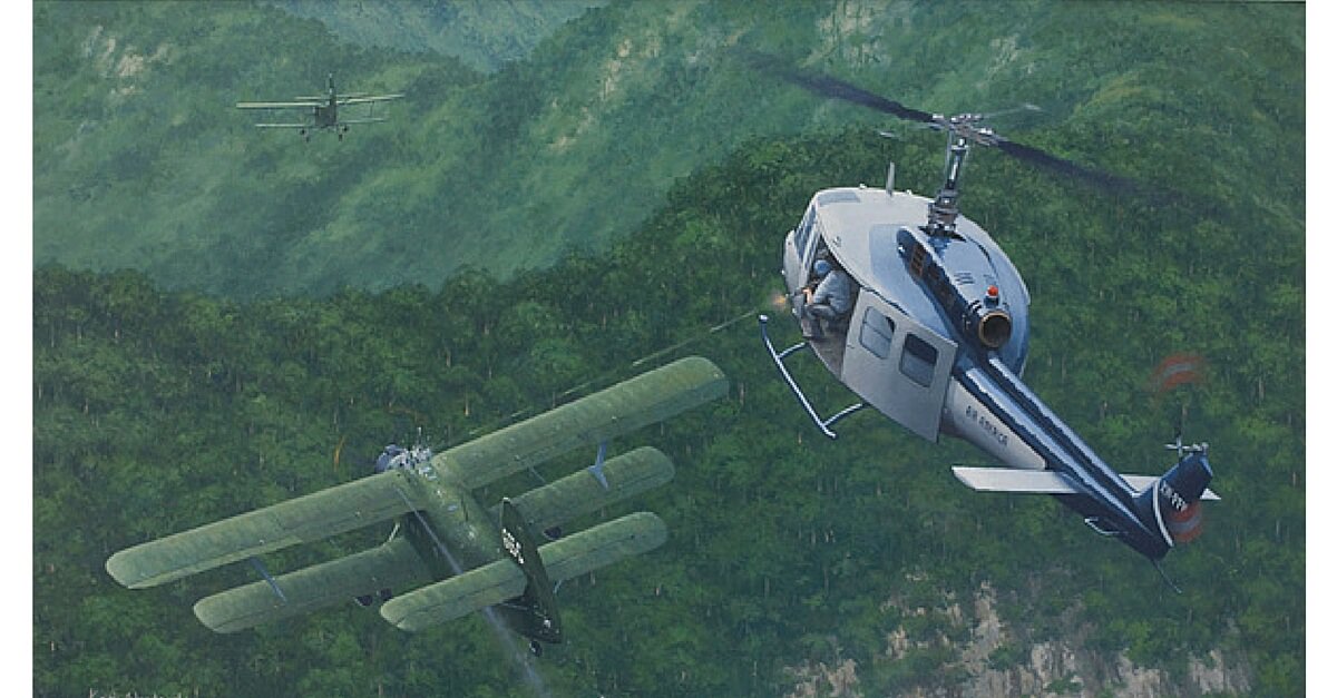 Painting of an Air America Bell 205 helicopter engaging two Vietnam People’s Air Force Antonov An-2 biplanes dropping 120 mm mortar rounds on Lima Site 85, Laos,12 January 1968.