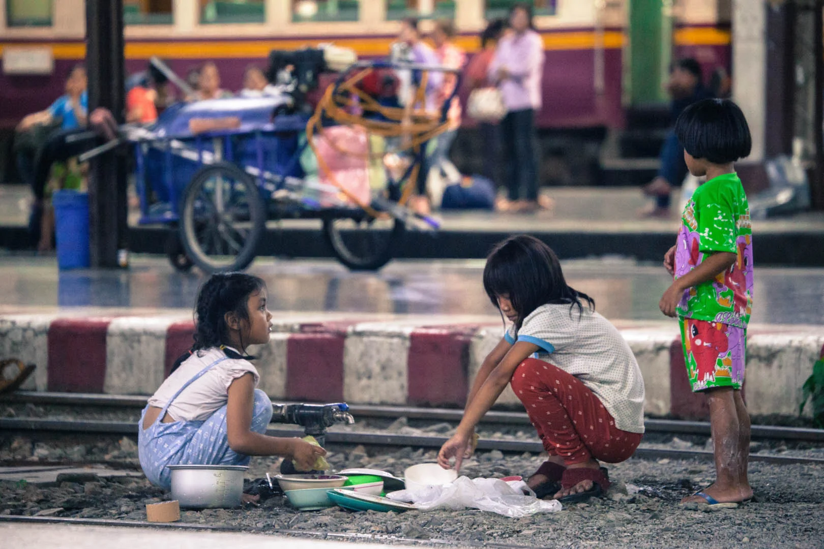 Local kids playing a cooking game on the rail tracks at the central train station in Bangkok.