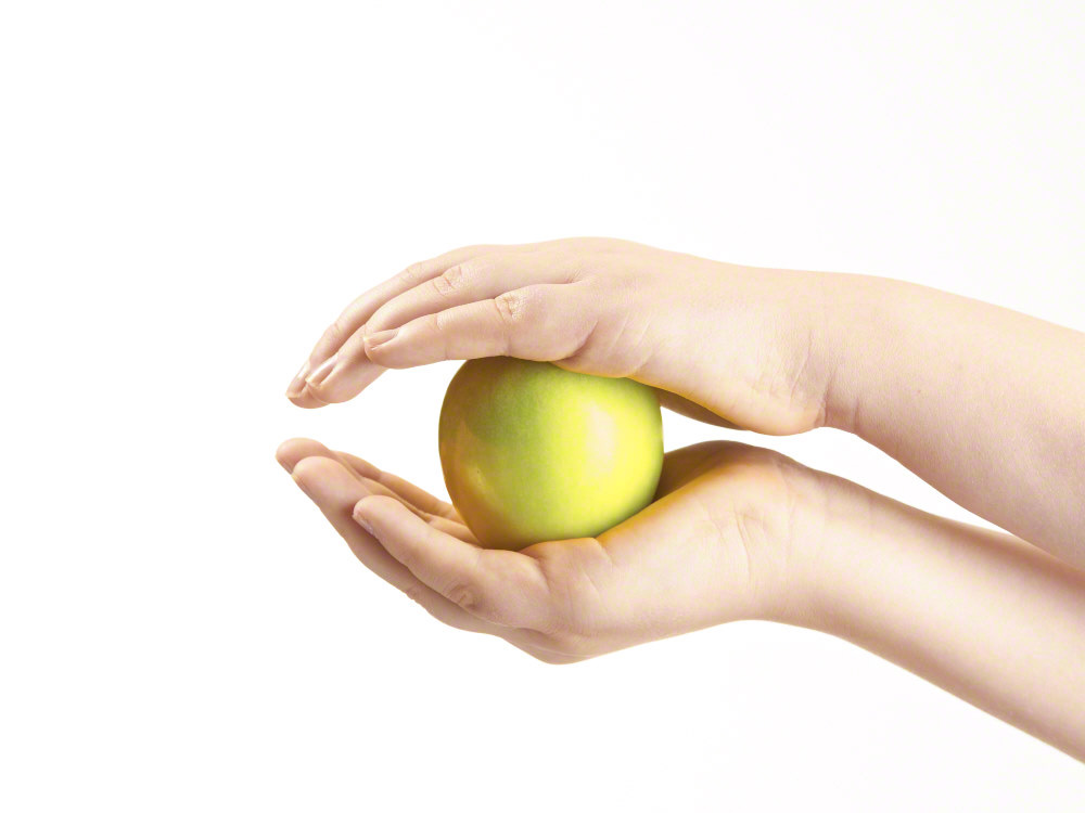 Apple sandwiched between childs hands