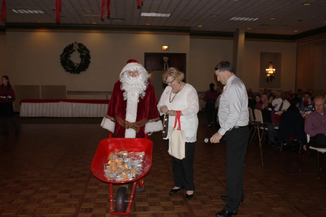 From left to Right: Santa, Beverly Hess, and Andrew Muller, Jr pictured as Santa surprised all of the RBMN employees with a gift of a 10 ounce bar of silver