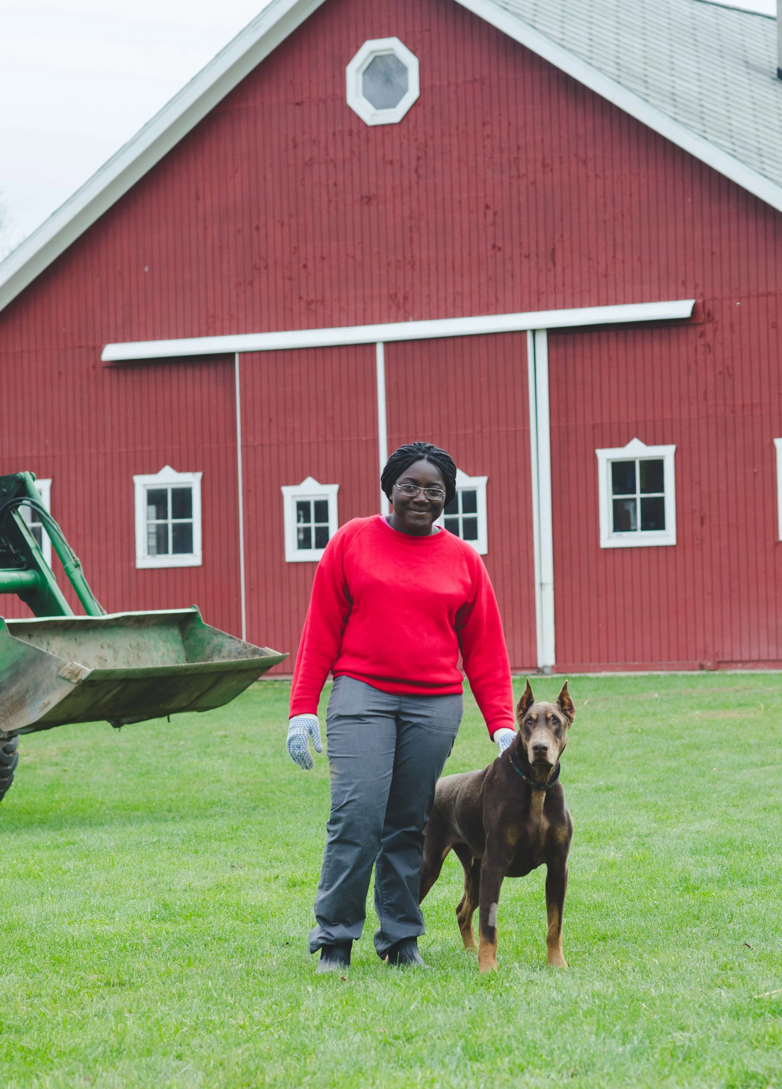This photo could not get any more Midwest: tractor, red barn, farm dog, work gloves, and muck boots