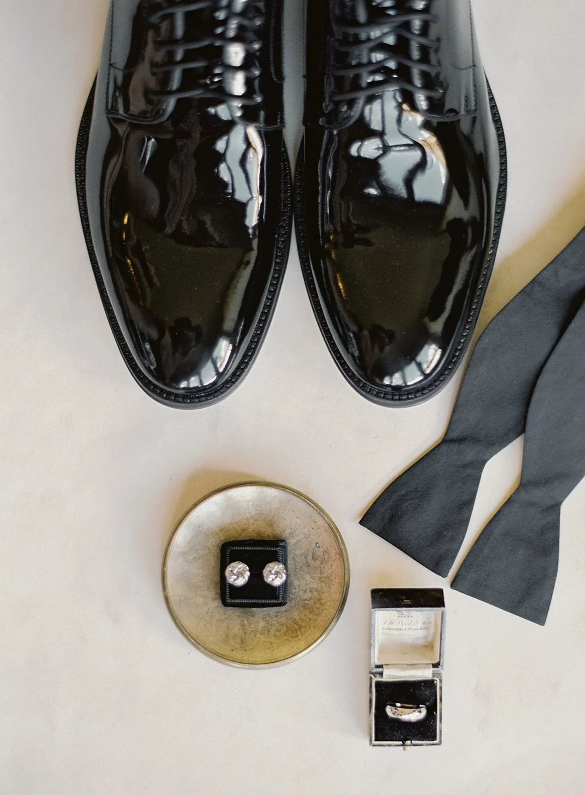 Black-tie groom’s shoes, cuff links, watch, and wedding details.