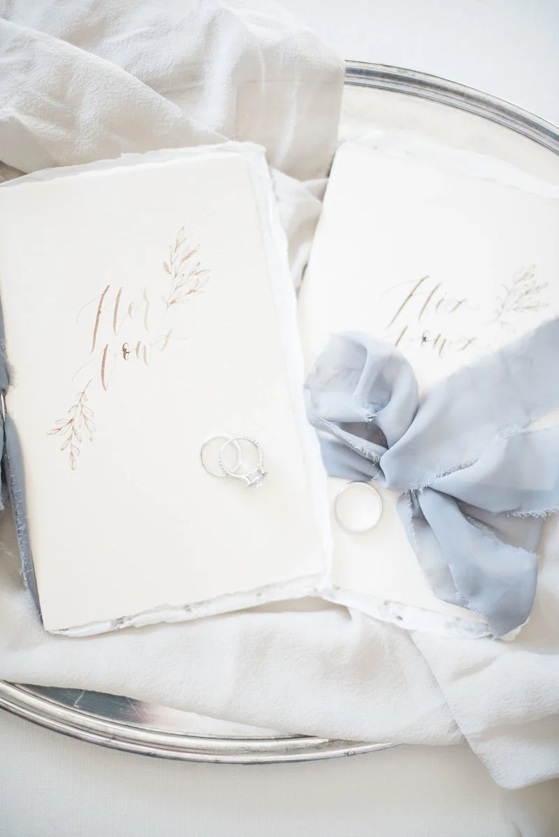 Beautiful calligraphy vow books by Jolie & Co with silk ribbon and wedding rings by The Styled Soiree, photo by Maribeth Photography