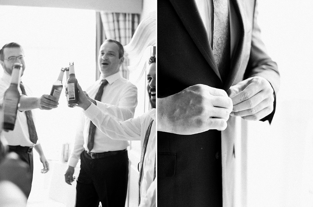 Groom getting ready with friends and buttoning his suit jacket