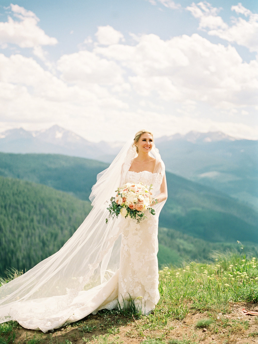 Bride with her veil and bouquet on top of a mountain in Vail