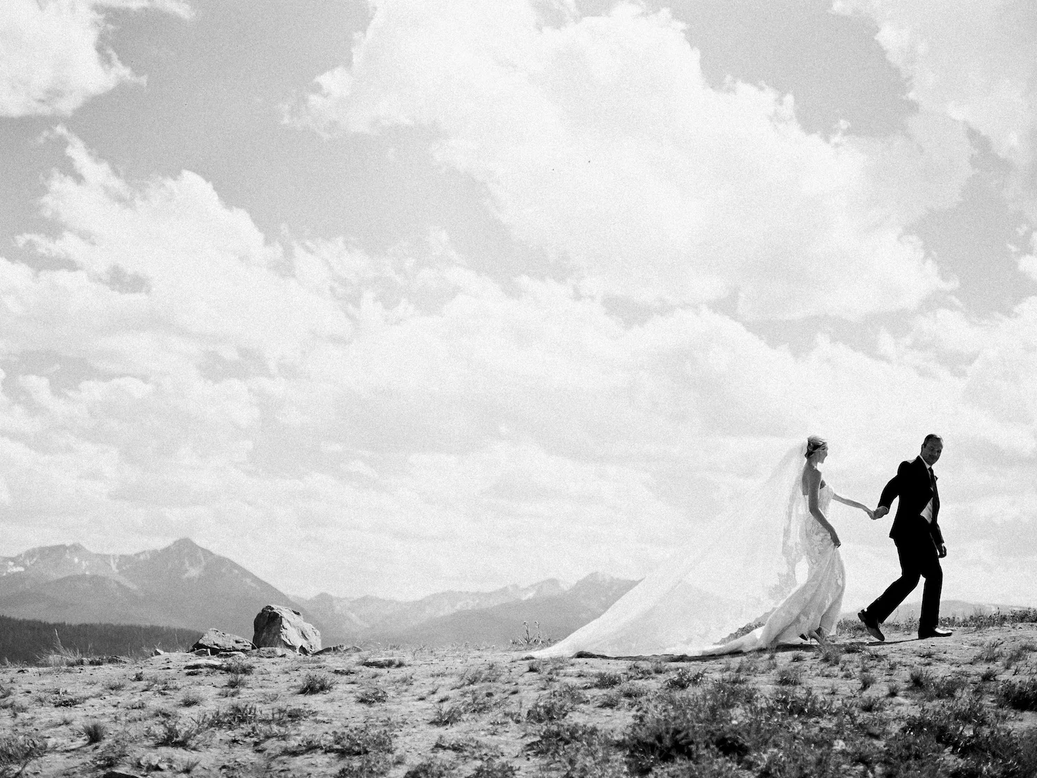 Black and white portrait of a bride and groom on top of a mountain
