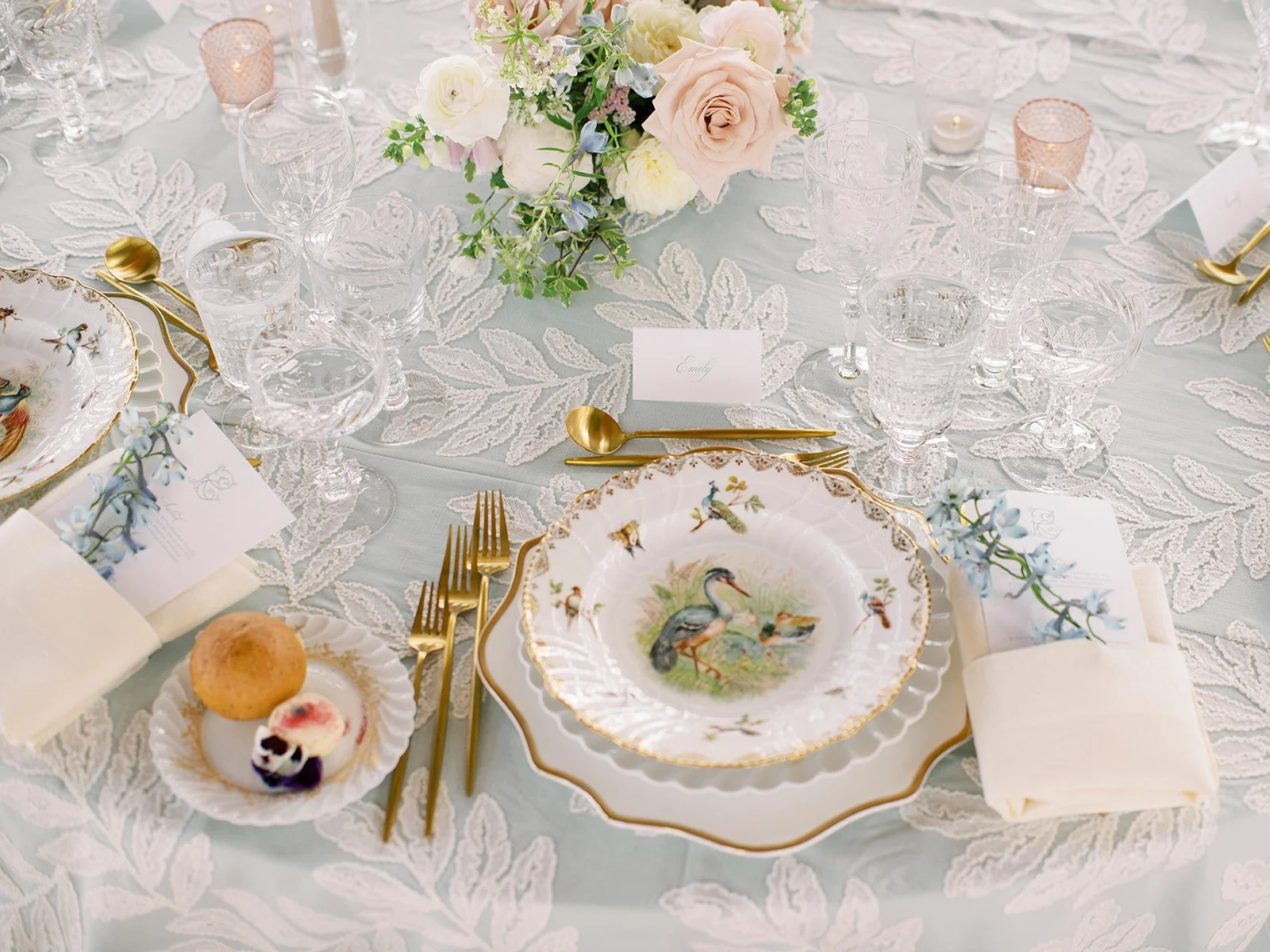 Antique porcelain, pale blue linens, gold flatware, and delicate flowers at each place setting.