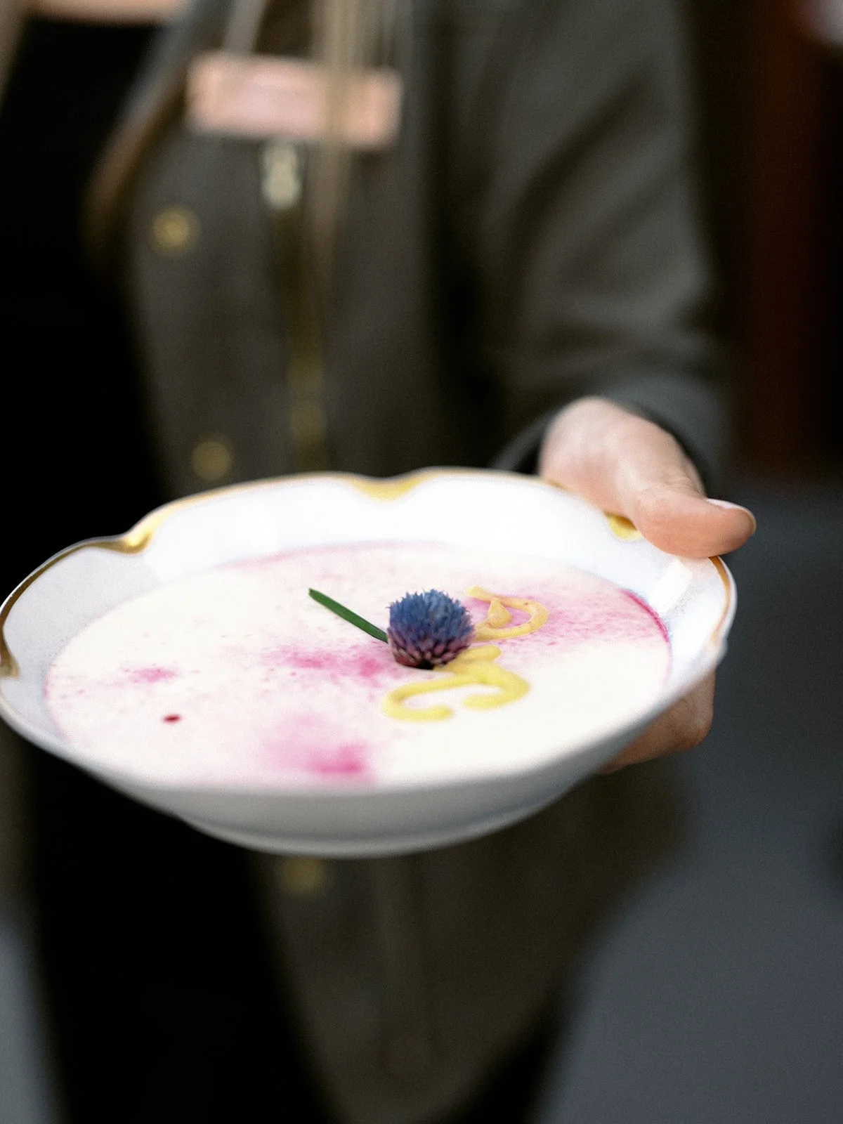 Elegantly plated soup presented during a five-course wedding dinner.