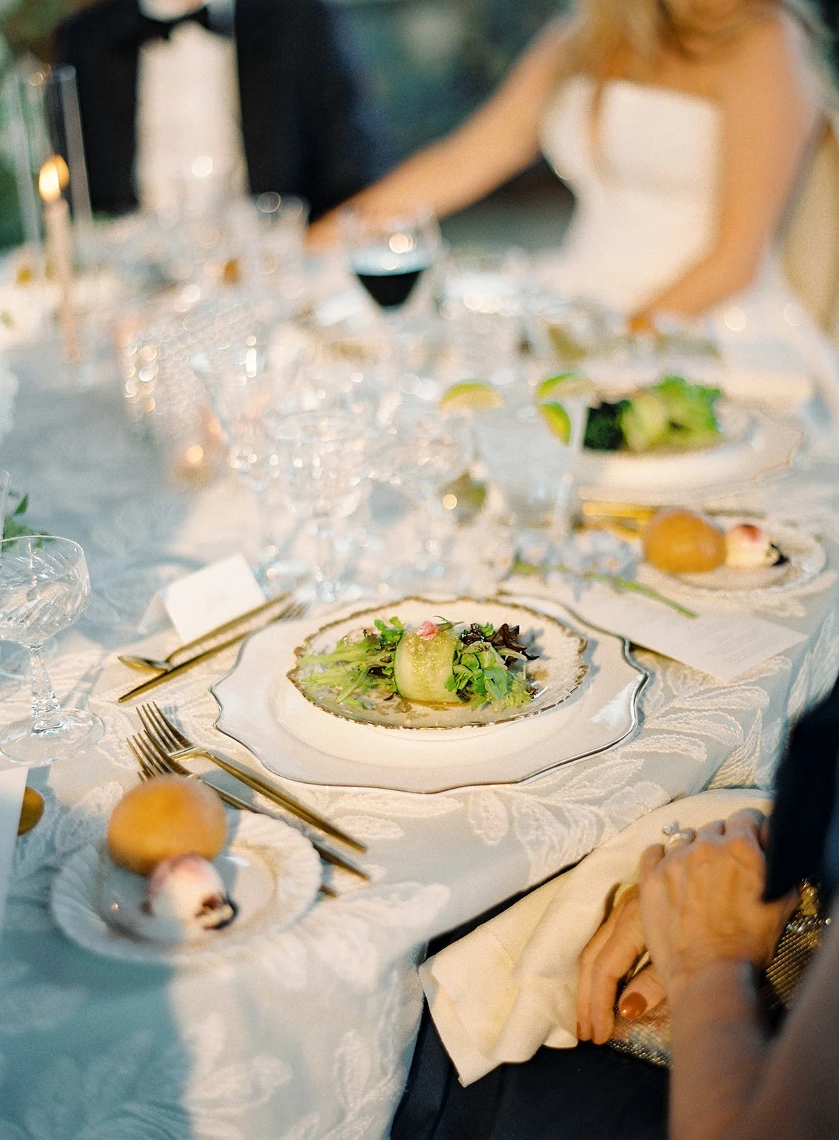 Guests enjoying a candlelit wedding dinner surrounded by flowers and antique tableware.