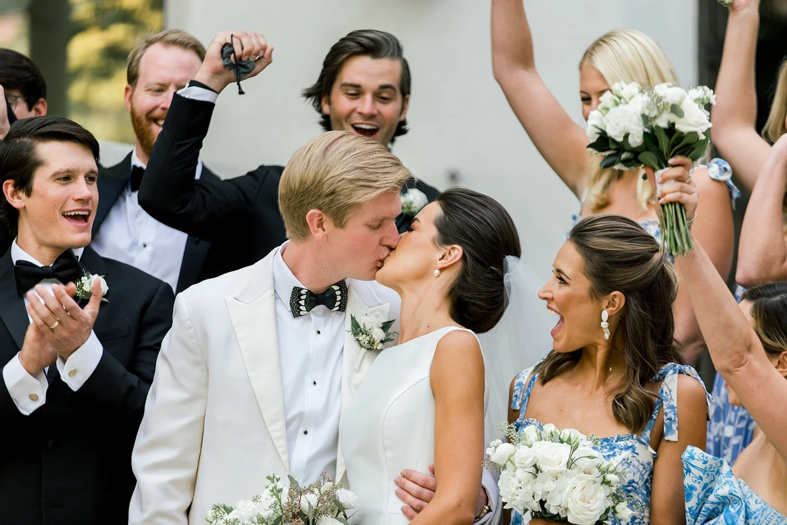 Newlyweds kissing while their wedding party cheers outside Vail Interfaith Chapel.