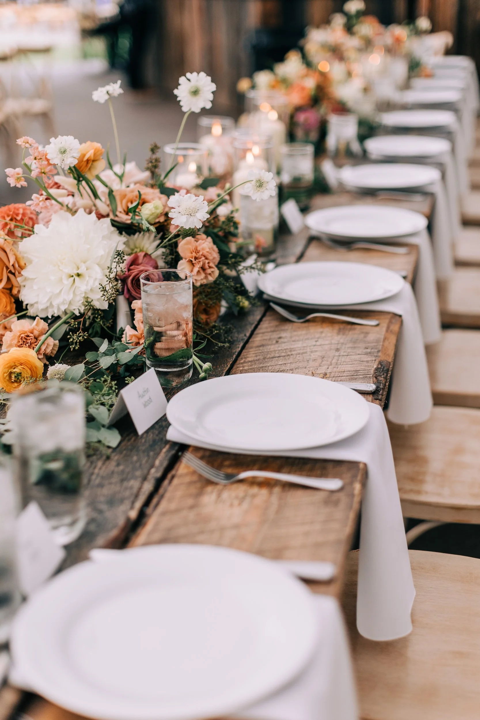 Long wedding reception table lined with abundant garden flowers