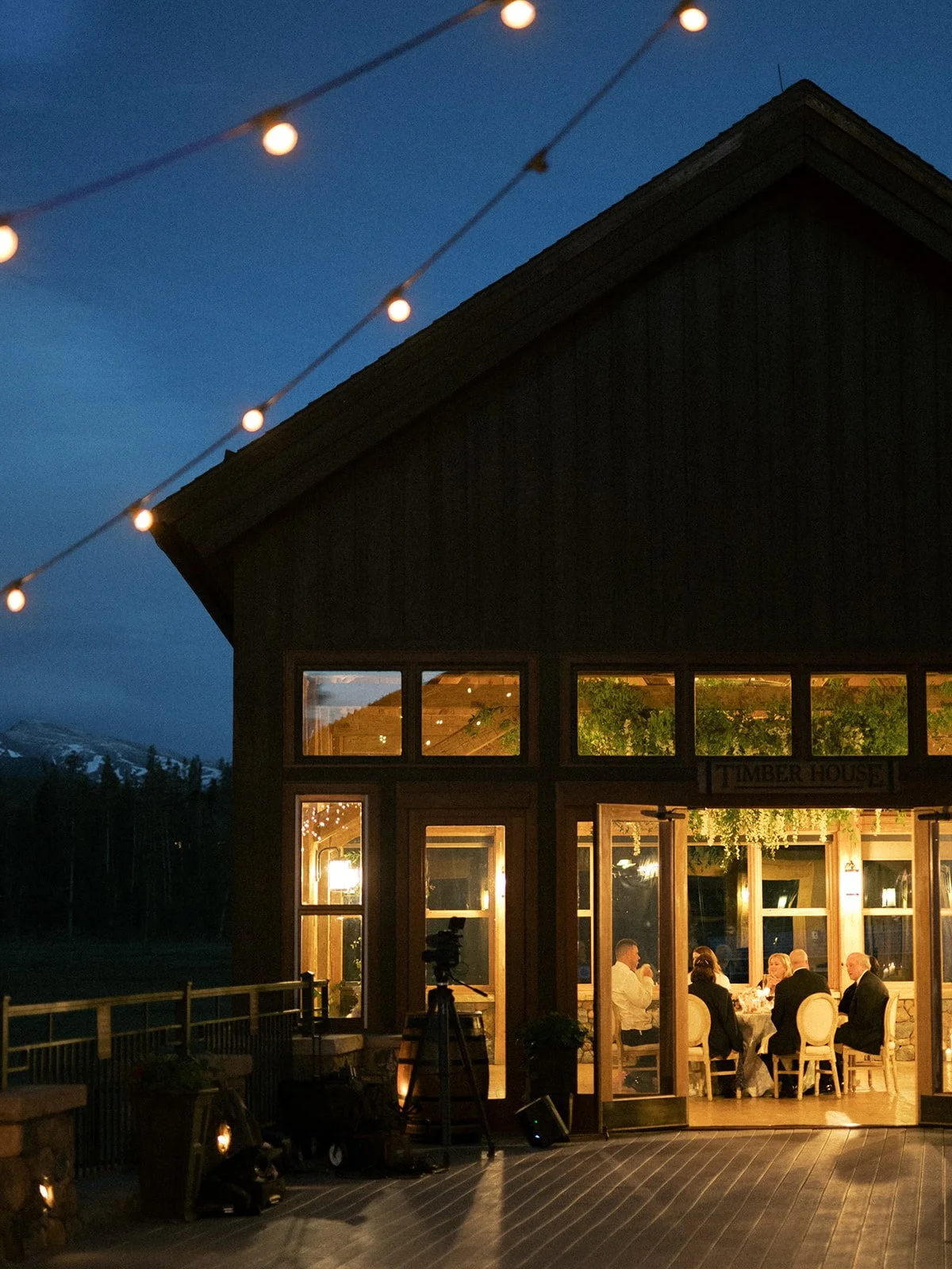 Timber House glowing beneath string lights during an evening wedding reception.