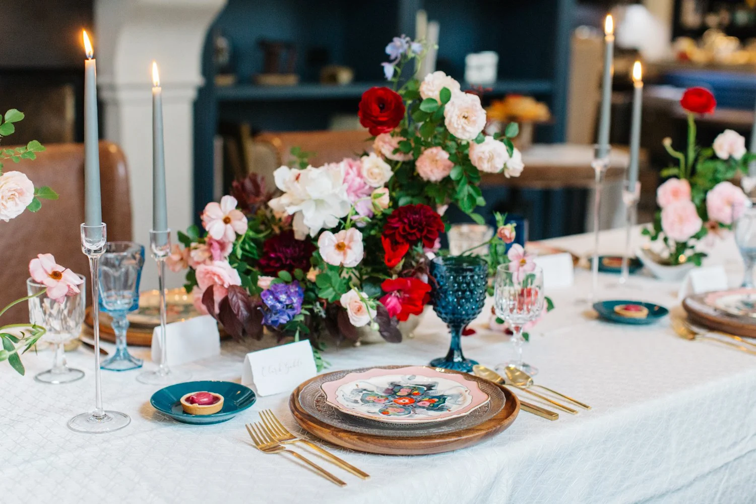 A thoughtfully designed reception table featuring vibrant floral arrangements, layered place settings, and artisan glassware for an editorial wedding aesthetic in Denver, Colorado. Photo by Emily Sacco.