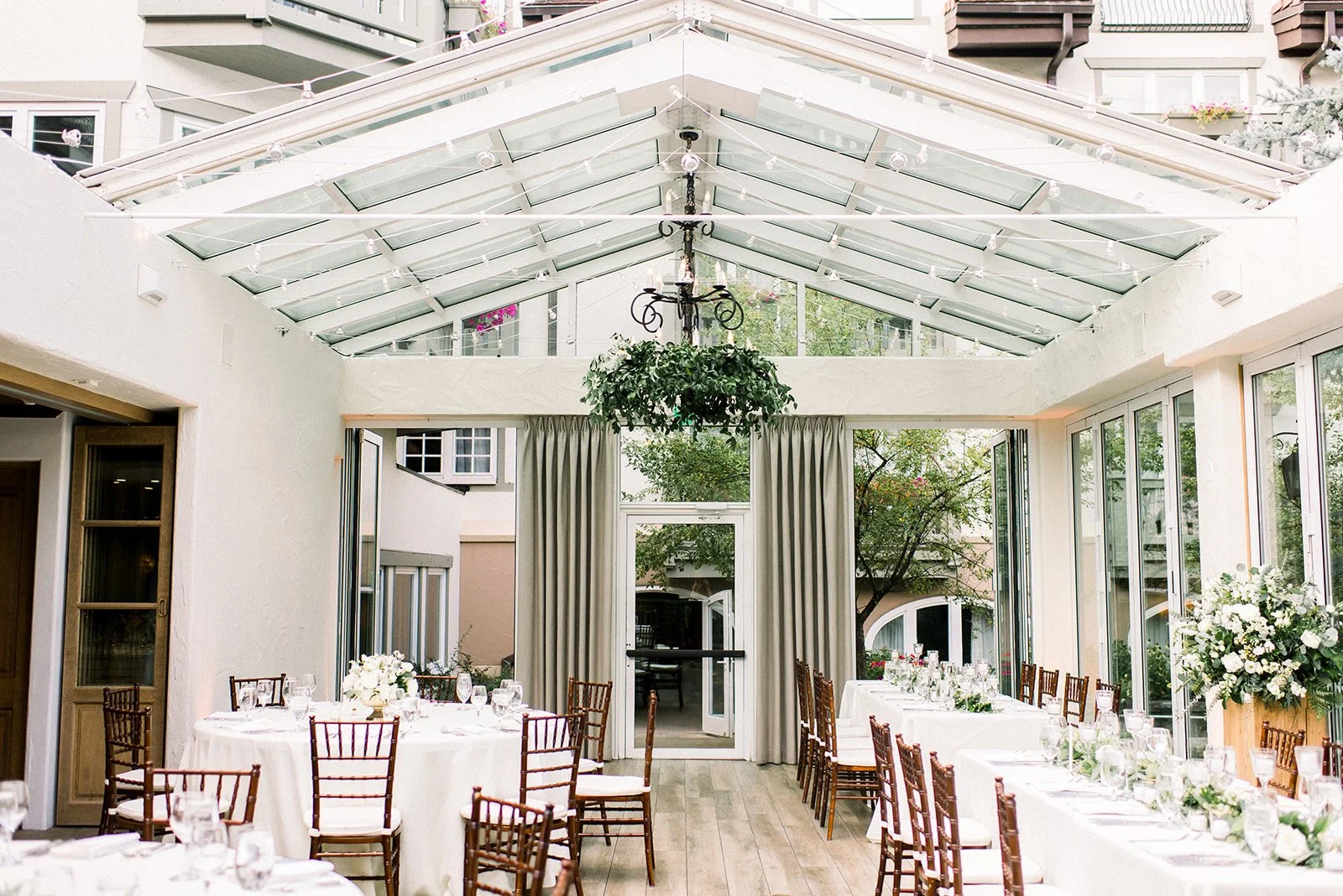 Glass-roofed Sonnenalp reception room set with white flowers and long tables.