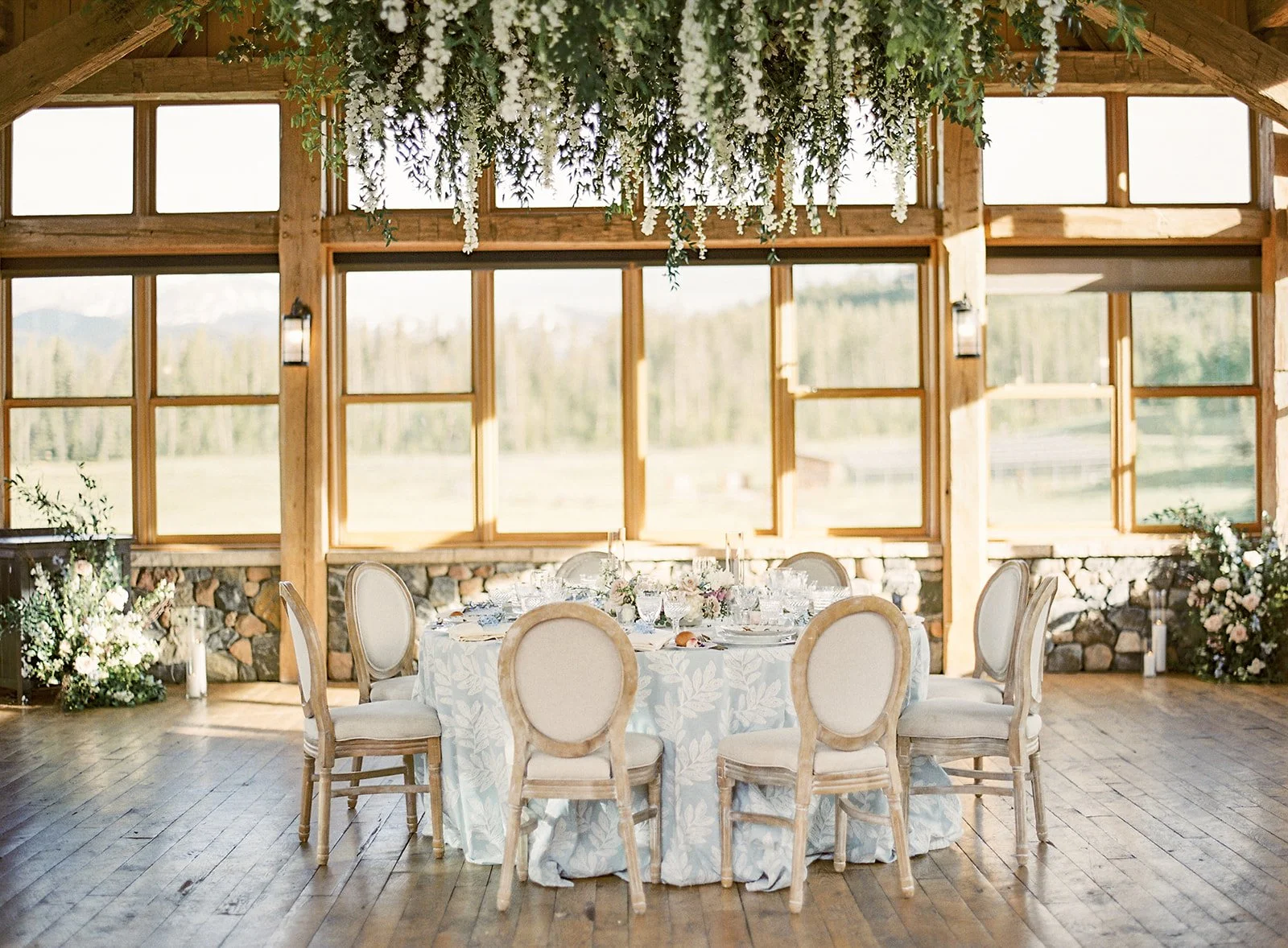 Intimate wedding dinner arranged beneath a hanging floral installation in Timber House.