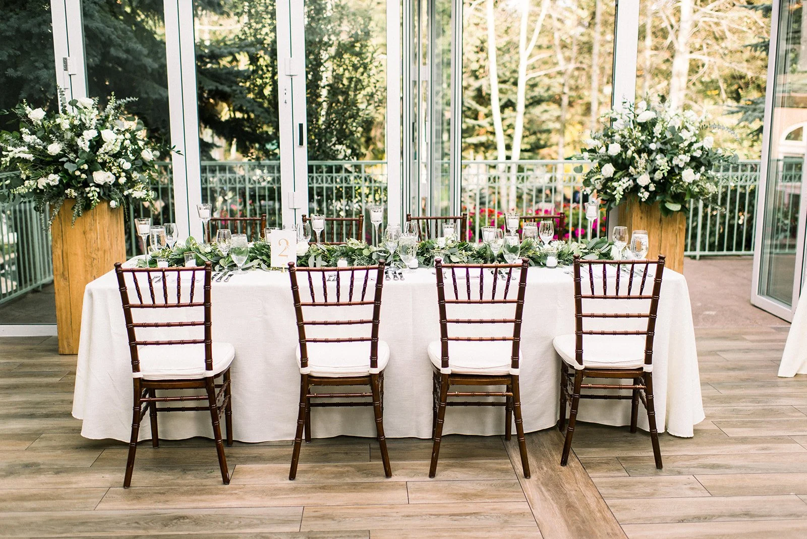 Head table framed by abundant white floral arrangements at The Sonnenalp.