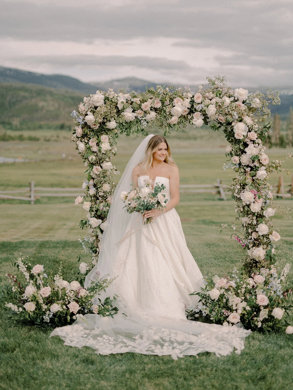 Bride photographed beneath the ceremony’s floral arch.