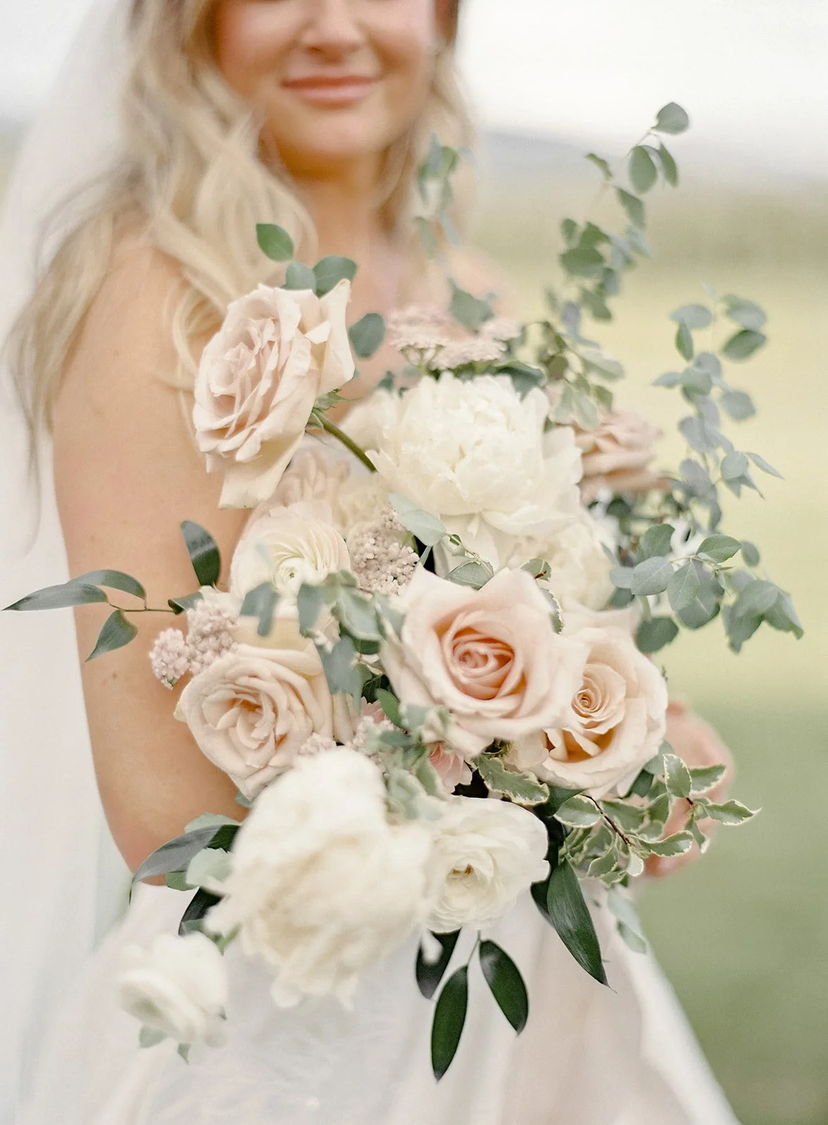 Bridal bouquet of white and blush flowers with soft greenery.