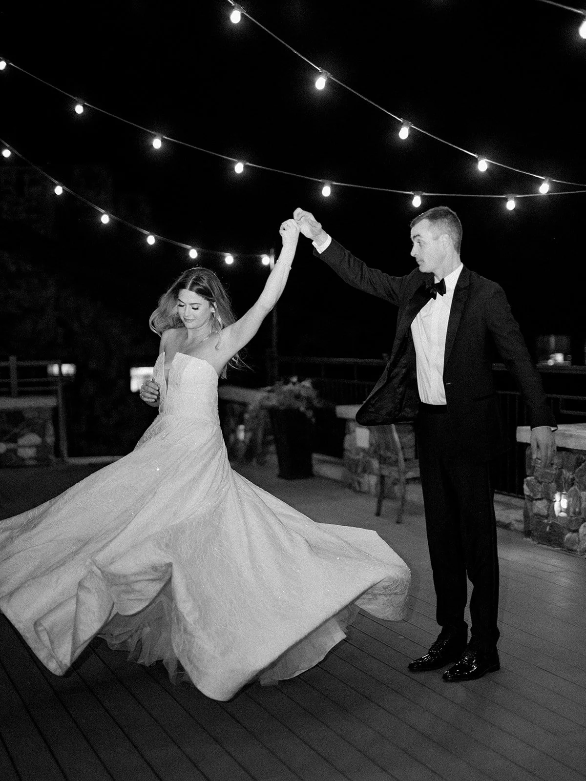 Newlyweds dancing beneath string lights at their Devil’s Thumb Ranch reception.