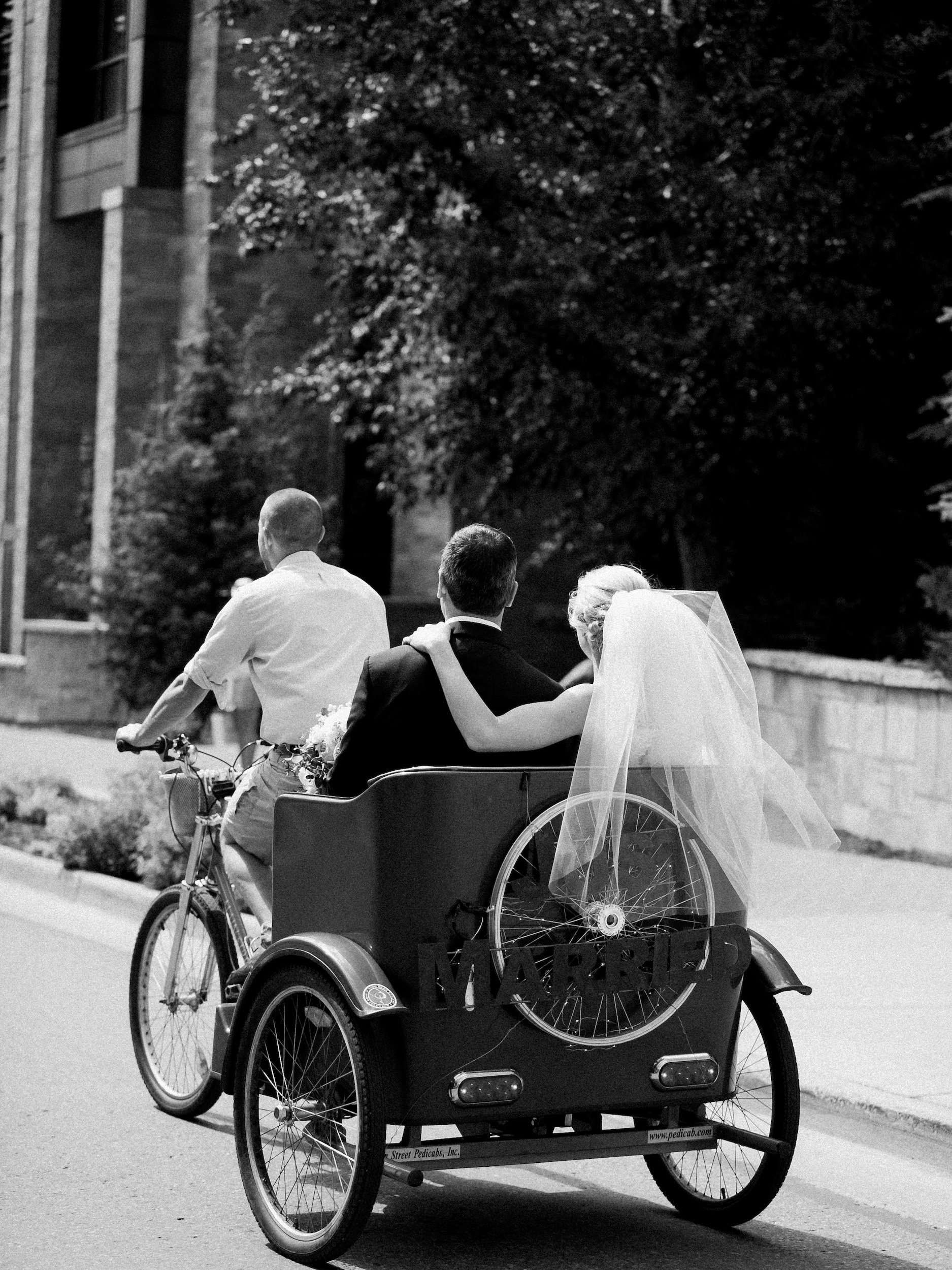 Newlyweds riding together in a pedicab after their ceremony