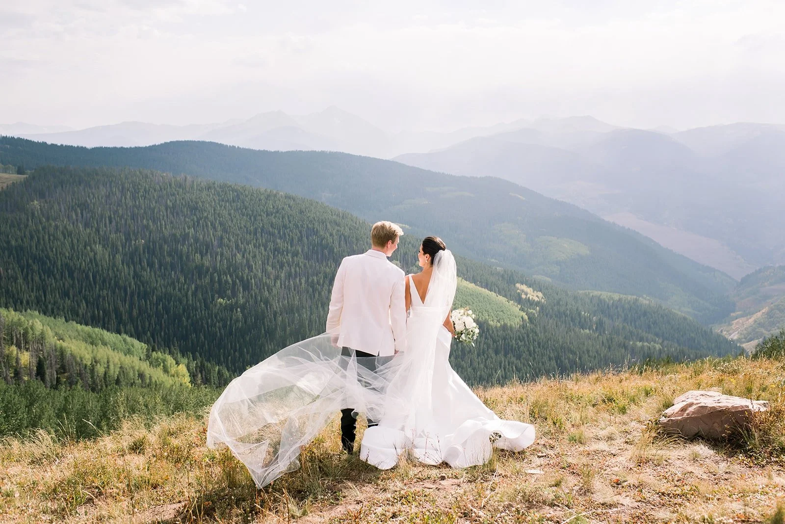 Newlywed couple overlooking the Rocky Mountains during a summer wedding in Vail, Colorado.