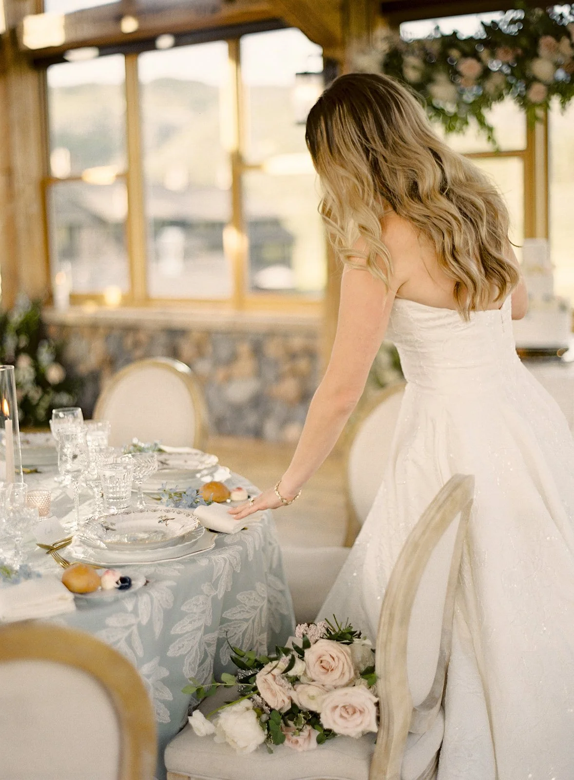 Bride admiring the floral and tabletop details arranged for her wedding dinner.
