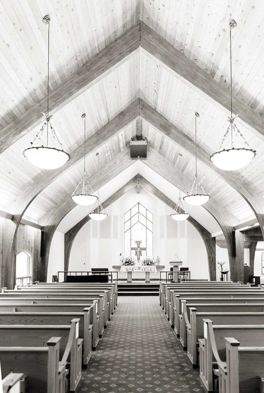 Empty interior of Vail Interfaith Chapel with wooden beams and a central aisle.