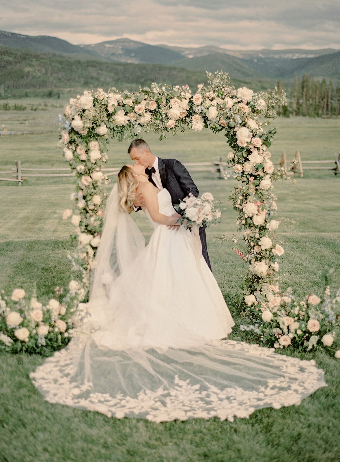 Bride and groom in black-tie attire surrounded by Colorado mountain scenery.
