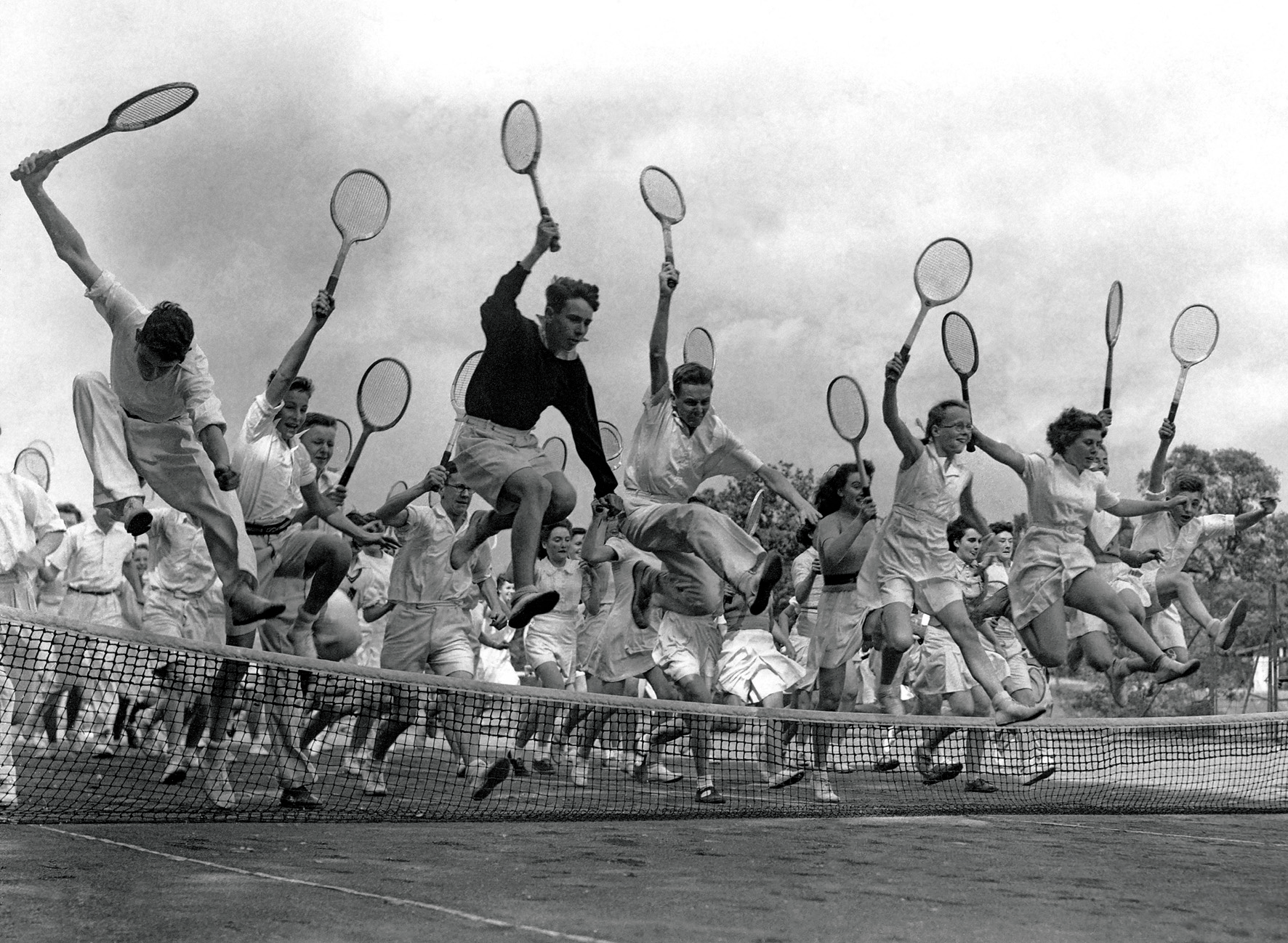   © The Stylish Life - Tennis, published by teNeues, www.teneues.com. Competitors at Tennis Tournament Jump over Net, Photo © Hulton-Deutsch Collection/CORBIS.  