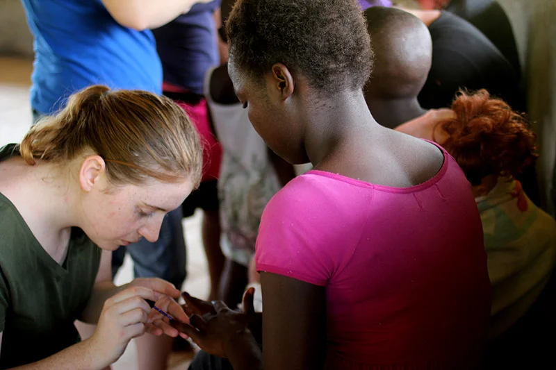 After the children got home from school, everyone gathered in the prayer hut. Some of the ladies on our team painted the girls' nails. Anita carefully painted this girl's nails purple with little flowers. She also cleaned windows, the guest house, and helped Elizabeth with the linens.