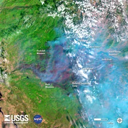 Above: "A recent image from the Landsat 8 satellite in the vicinity of Yosemite National Park, California, during the Rim Fire (August 31). Started on August 17, the Rim Fire had burned over 219,000 acres by August 31 (an area nearly 15 times the size of Manhattan Island). Image is false-colored using bands 6, 5, 4 to allow identification of critical vegetation and fuels information that will help firefighters and emergency managers. In the image fire appears bright red, vegetation is green, smoke is blue, clouds are white, and bare ground is tan-colored."