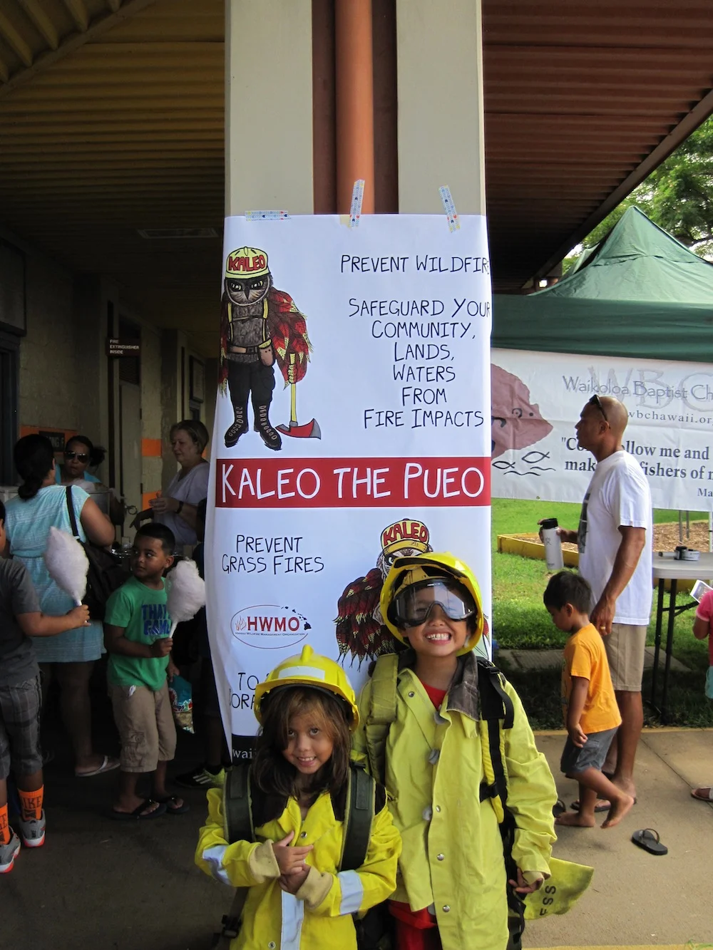 Dressing up in wildland fire gear and posing in front of Kaleo the Pueo (and cotton candy enthusiasts!)