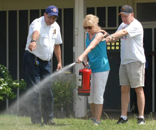 "Fire Battalion Chief Joseph Farias left indicates where to aim the spray to Mary and Dale Watson at a fire extinguisher workshop Saturday at the Waikoloa Stables. Laura Shimabuku/West Hawaii Today"