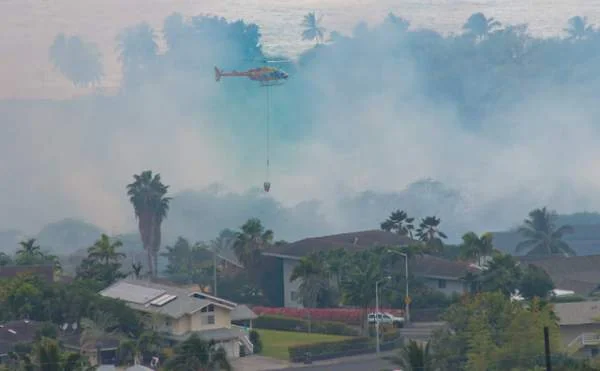 "A Hawaii County helicopter performs a water drop on a brush fire that threatened homes in the Komohana Kai subdivision of Kailua-Kona on Wednesday. (Photo courtesy Denny Miller/Special to West Hawaii Today)"