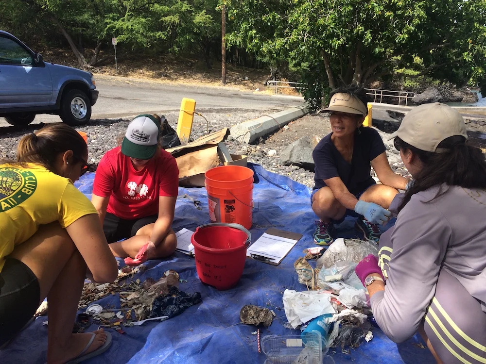 Cynthia Ho (top right) leads the charge to clean and sort debris at Puako Boat Ramp to prevent coral reef pollution and wildfires.