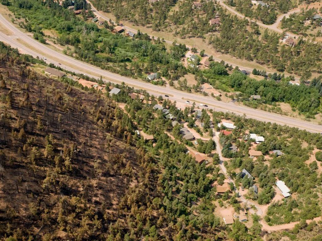 "Where wildfire meets homes, the fire suppression response may protect homes but distort the full cost of insuring the homes from wildfires. Waldo Canyon Fire, Colorado Springs, CO, 2012." Credit: USFS