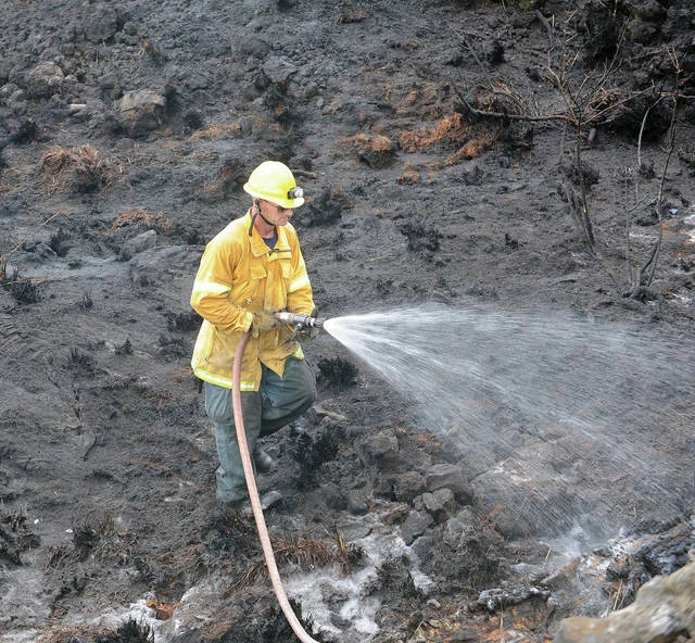 "A Hawaii County firefighter douses a brush fire off Highway 190 near mile marker 18 Friday afternoon." Laura Ruminski / West Hawaii Today