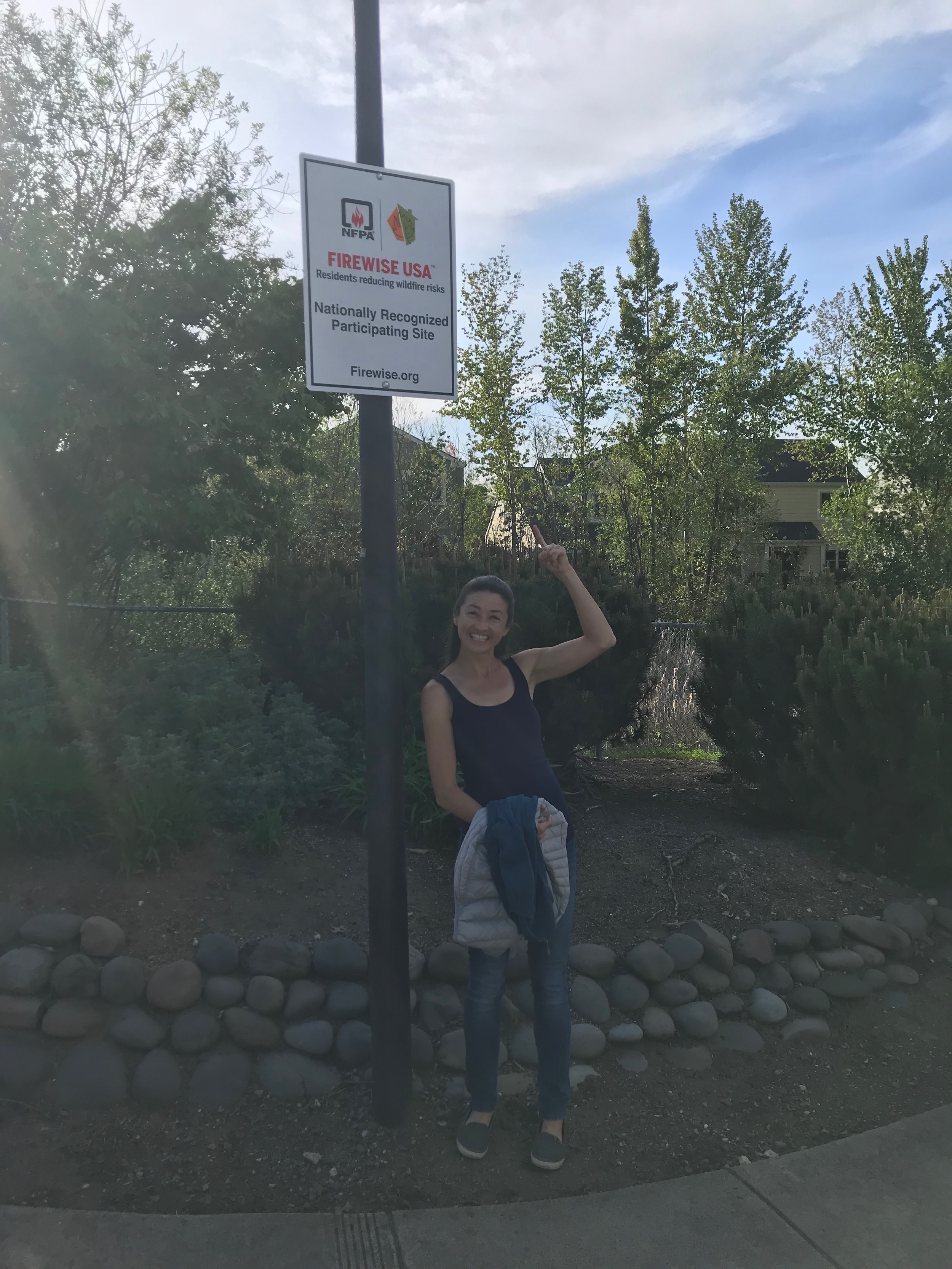 Elizabeth Pickett pointing out a Firewise USA sign.